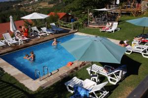 a group of people in a swimming pool with an umbrella at Casas do Pastor in Seia
