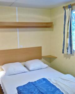 a bedroom with a bed with two pillows at Mobil-home St Georges in Saint-Georges-de-Didonne