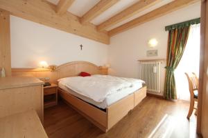 a bedroom with a large bed and a desk at Hotel El Pilon in Pozza di Fassa
