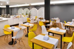 a dining room with tables and yellow chairs at Hotel Hispano in Montevideo