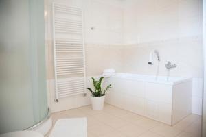a white bathroom with a sink and a plant at Hotel Eminent in Stupava