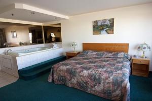 a hotel room with a bed and a bath tub at Western Budget Motel Bonnyville in Bonnyville
