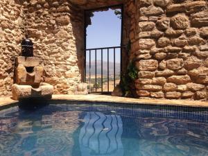 una piscina di fronte a un edificio in pietra con finestra di Salvatierra Guest House a Ronda