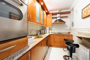 una cocina con armarios de madera y un aparato de acero inoxidable en Apartamento frente al Guggenheim con wifi y parking privado gratis, en Bilbao