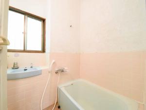 a pink bathroom with a tub and a sink at Shurin in Tsumagoi