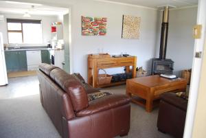 a living room with a leather couch and a stove at Judge Rock Exclusive Vineyard Cottage Accommodation in Alexandra