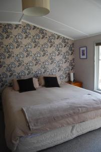 1 dormitorio con 1 cama grande y papel pintado con motivos florales en Judge Rock Exclusive Vineyard Cottage Accommodation en Alexandra