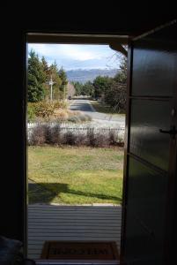 an open door with a view of a yard at Judge Rock Exclusive Vineyard Cottage Accommodation in Alexandra