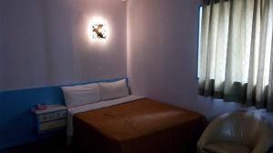 um pequeno quarto com uma pequena cama e uma janela em Reui Chung Hotel em Kaohsiung