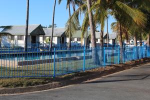 a blue fence in front of a house with palm trees at Central Tourist Park in Mackay