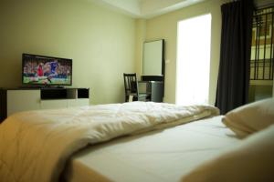 um quarto com uma cama branca e uma televisão em The Suvarnabhumi Apartment em Bang Kew Yai