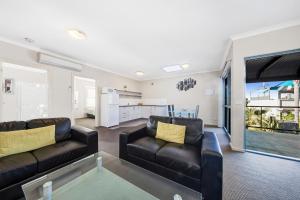 ein Wohnzimmer mit zwei schwarzen Ledersofas in der Unterkunft Moonlight Bay Apartments in Rye