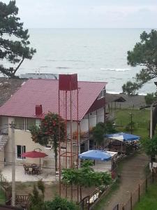 a building with tables and umbrellas in front of the ocean at Ureki GuestHouse in Ureki