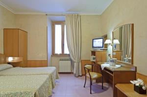 una camera d'albergo con letto, scrivania e specchio di Hotel Museum a Roma