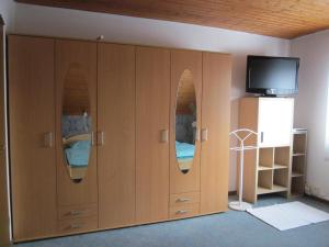 オーバーアスバッハにあるPrivatunterkunft Schonlauの壁にテレビが付く木製キャビネット付きの客室です。