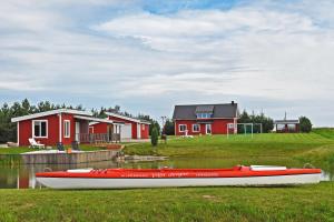 una barca rossa seduta sull'erba di fronte a una casa di Villa Ievynė a Paežeriai
