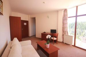 a living room with a couch and a desk with a computer at Dafovska Hotel in Pamporovo