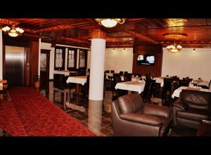 a dining room with tables and leather chairs and a television at Simre Hotel in Amasya