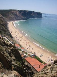 a beach with a bunch of people and the ocean at casa da ponte aljezur center in Aljezur