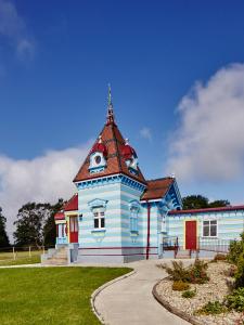 un bâtiment bleu avec une tour d'horloge dans un parc dans l'établissement The Dolls House, à Wexford