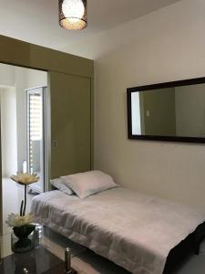 1 dormitorio con cama y espejo grande en Taal View Condo by Liza en Tagaytay