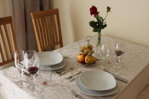een tafel met borden en glazen en een vaas met een roos bij Ferienwohnung SONNENUHR in Bacharach