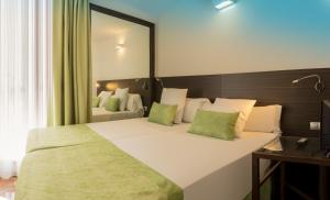 una camera da letto con un grande letto bianco con cuscini verdi di Magic Tropical Splash a Cala de Finestrat