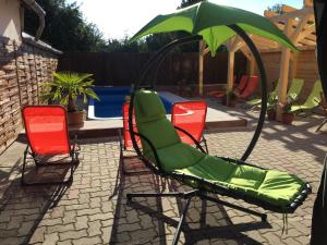 een groep stoelen en een parasol naast een zwembad bij Napház Panzió in Tiszafüred