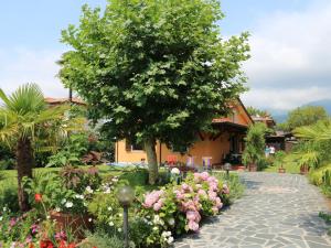 a garden with flowers and a tree and a building at Bungalow near beach with covered terrace at Tuscan Coast in Massa