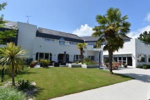 un bâtiment blanc avec des palmiers dans la cour dans l'établissement Hôtel du Golf Saint-Laurent, à Ploemel