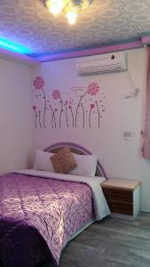 鵝鑾的住宿－華宏海景旅店 ，卧室配有一张紫色床,墙上挂着鲜花