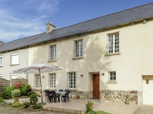 a white house with an umbrella and tables and chairs at Holiday home with pretty terrace and garden, near the Paimpont forest in Lanrelas