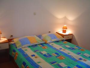 a bedroom with a bed with a colorful comforter and pillows at Apartments & Rooms Lo & Mar in Medulin