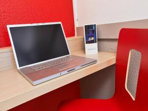 a laptop computer sitting on a desk with a red chair at Premiere Classe Lille Sud - Seclin in Seclin