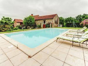 a swimming pool with two chairs and a house at Cozy Holiday Home in Besse with Swimming Pool in Villefranche-du-Périgord