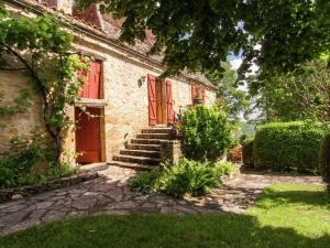 una casa de ladrillo con puertas rojas y un patio en Farmhouse in Saint Cybranet with Private Garden en Saint-Cybranet