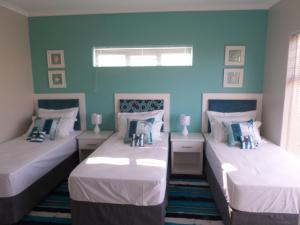 two twin beds in a room with blue walls at Beach House Bliss in Langebaan