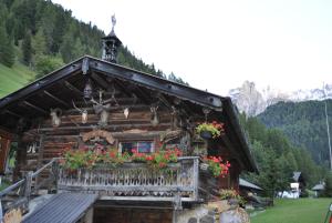 a log cabin with flowers on a balcony at Romantik Villa Cesanueva in Selva di Val Gardena