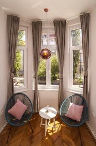 due sedie e un tavolo in una stanza con finestre di Doma Zagreb Aparthotel a Zagabria