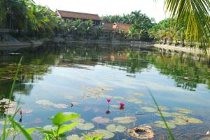 a pond with lily pads and palm trees at Tam Coc Westlake Homestay in Ninh Binh