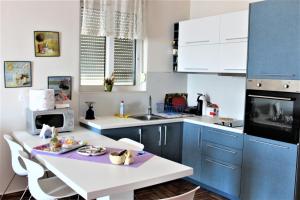 a kitchen with blue and white cabinets and a table at Seaside Apartment in Sarandë