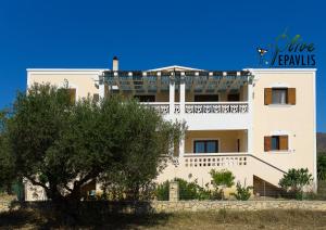 a white building with a tree in front of it at Olive Epavlis in Karpathos