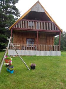 a log cabin with flowers in front of it at Priedīši in Aglona