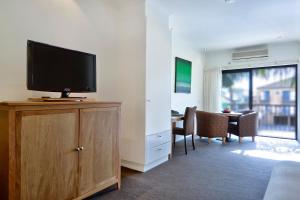a living room with a flat screen tv on a wooden cabinet at BEST WESTERN Geelong Motor Inn & Serviced Apartments in Geelong