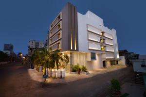 a white building with palm trees in front of it at Bizz The Hotel in Rajkot