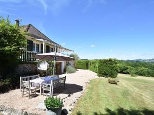 a patio with a table and an umbrella in front of a house at Spacious vacation home with pool in Chaumard