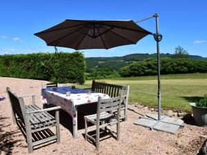 una mesa y dos sillas bajo una sombrilla en Spacious vacation home with pool, en Chaumard