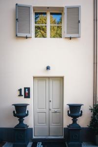 a white house with two vases in front of a door at Palazzo Gozzi Bed & Beauty in Parma