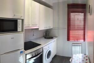 a kitchen with white cabinets and a sink and a microwave at Betiko in Vitoria-Gasteiz