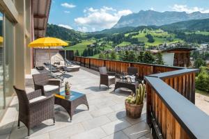 a balcony with chairs and a table and an umbrella at Hotel Serena in Badia